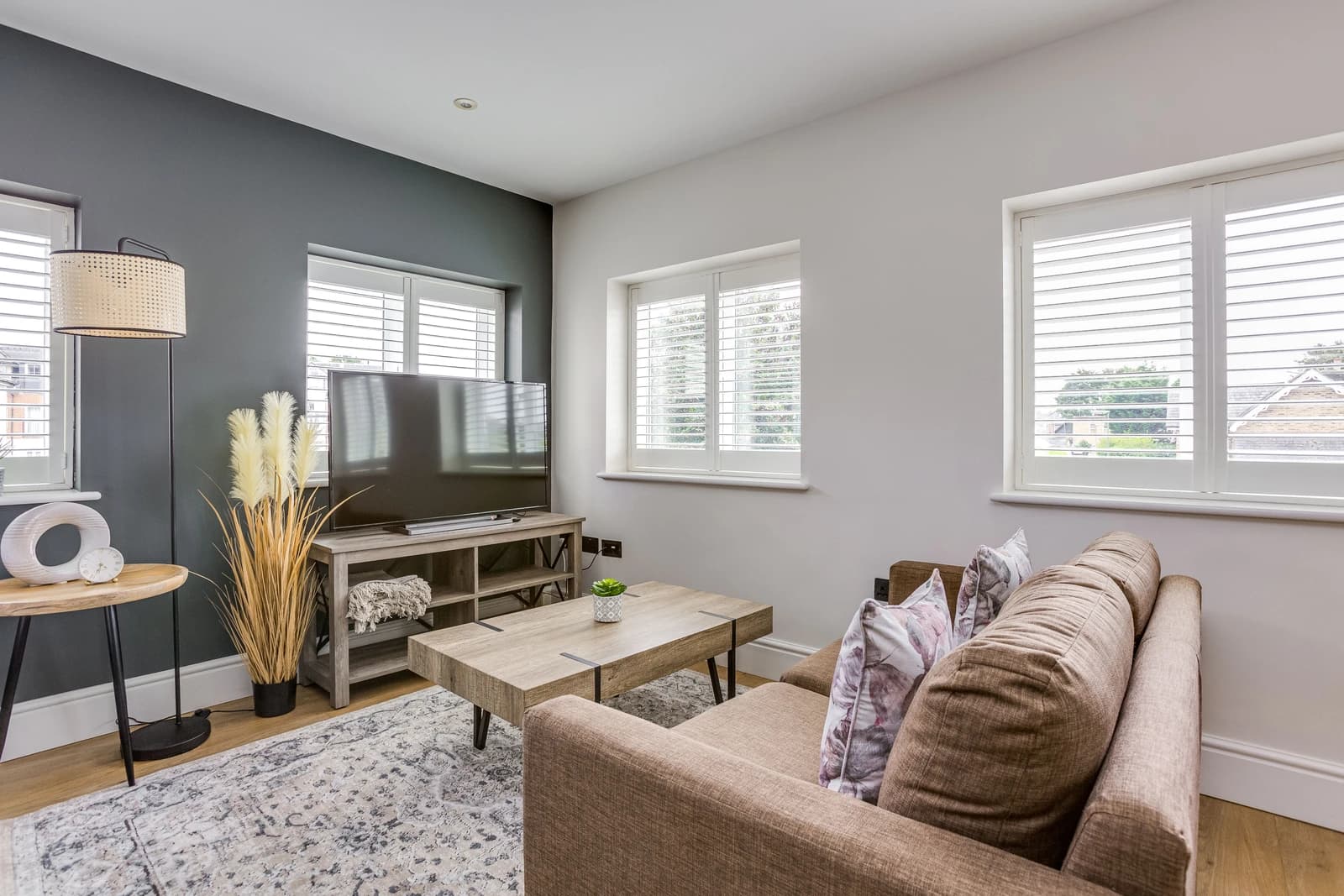 Open-plan living area with brown sofa, small double bed and kitchen at Boon House Flat 2, Egham